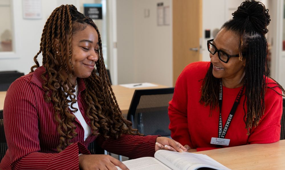 Student sitting at a table with a tutor.